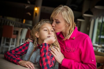 Portrait happy loving family, mother and daughter sitting in city cozy café and hugging. Mother and daughter smiling sincerely. Styling family, true emotions, good day 