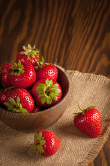 Macro photo of fresh ripe red strawberry in a wooden bowl on rustic background. Organic natural products.