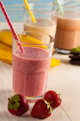 Long glasses of milkshakes with chocolate, strawberry, banana, with ice cream on white and blue background. Shakes and smoothies. Milk shake and cocktail for summer.