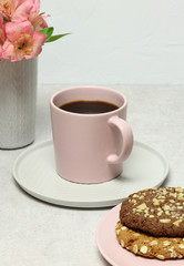 Cup of coffee, cakes, fresh flowers on grey stone table