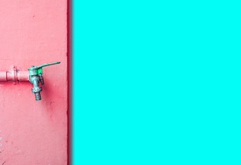 Faucet on the wall pink and aqua blue wall.