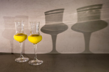 Two glasses of egg liqueur on grey texture background