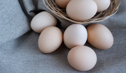 Chicken eggs in a basket. Eggs in a wicker basket on linen gray fabric. Close-up