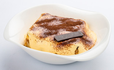 Delicious Tiramisu cake with coffee beans on a plate on a light background.
