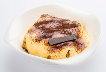 Delicious Tiramisu cake with coffee beans on a plate on a light background.