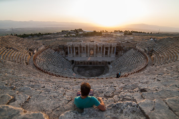 Men sitting on the steps of the ancient amphitheater Beautiful young men traveler admiring the...