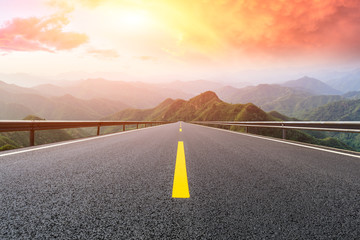 Empty asphalt road and mountains with beautiful clouds at sunset
