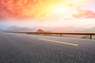 Empty asphalt road and mountains with beautiful clouds at sunset
