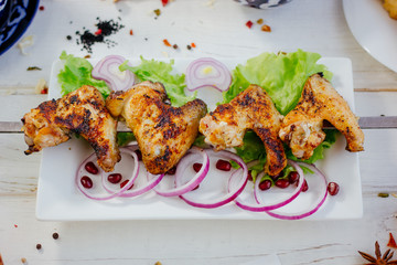 Chicken wings on skewer over the white plate.