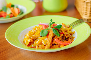 Farfalle pasta with the chicken and tomatoes on a green plate.