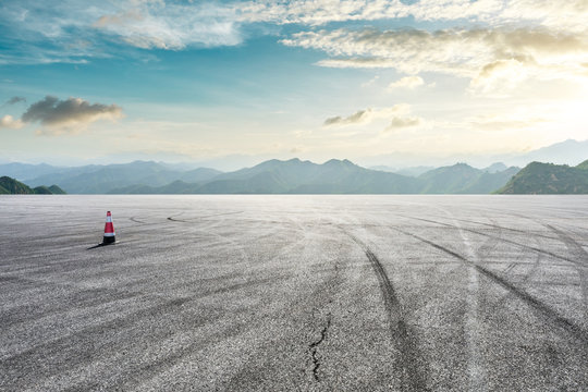Asphalt race track ground and mountain with sunset clouds
