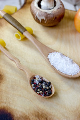 Fototapeta na wymiar Sea salt and black pepper in wooden spoons over wooden kitchen board.
