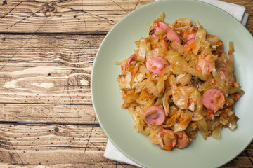 Stewed cabbage with sausages in a plate on the table. Selective focus.
