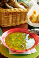 Lentil soup in a red plate over a wooden table.