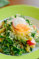 Salad with radish, carrot, lettuce and cheese in a green plate.