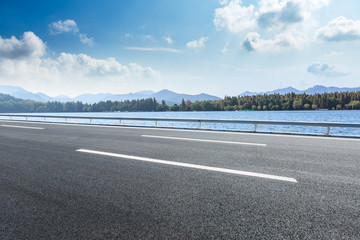 Empty asphalt road and mountains with lake landscape