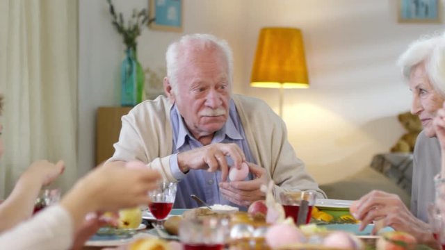Panning medium shot of grandparents talking to grandson during family dinner on Easter sunday