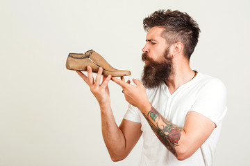 Bearded shoemaker on white background, copy space. Bearded man holding last shoe. Serious young...
