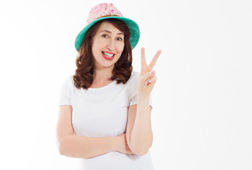 Middle age happy face woman showing victory peace sign isolated on white background. Female in beach hat and template t shirt with copy space. Holiday and vacation concept. Banner