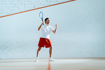 Full length view of happy squash player with racket showing yes gesture
