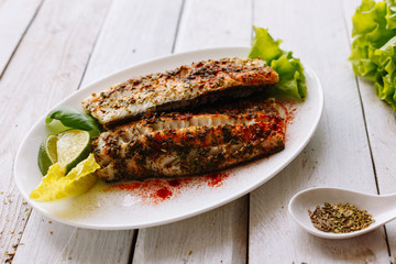 Baked fish wild spicy spices and lime. Wooden white table. Diet. Dinner. Homemade.