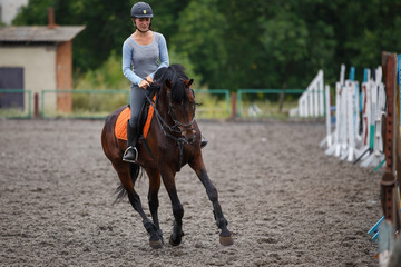 Young girl riding bay horse on equestrian sport training