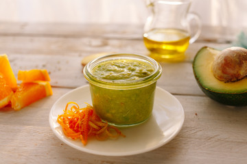 Organic sauce with avocado, orange and oil. White wooden table. Diet. Homemade.