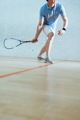 Partial view of sportsman in blue polo shirt playing squash