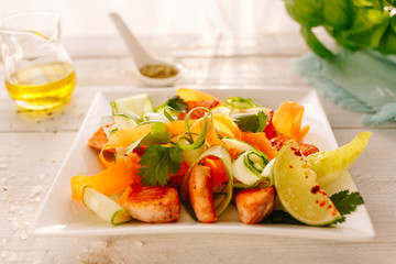 Salad with grilled chicken and vegetables. Cucumber, carrot, lime. Wooden white table. Ingridients.