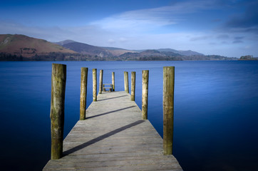 Obraz premium Ashness Bridge jetty on Derwentwater in the Lake district National park England showing a calm Lake and blue sky. 