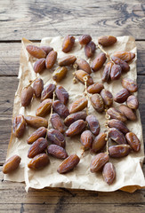 Dried dates fruits on a branch on a wooden table.