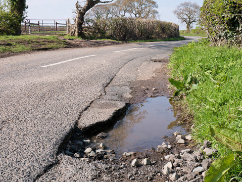 Unrepaired surface damage to tarmac on a rural road