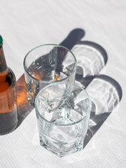 Two cristal glasses and one beer bottle on a white paper tablecloth.