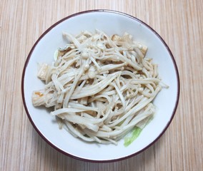 Top view of Stir fried Golden Mushroom or Enokitake with butter on white plate, on wooden table (Flammulina velutipes, Winter Mushroom)