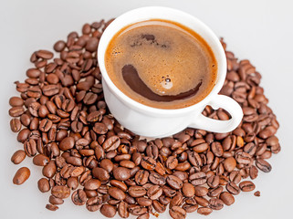 Coffee beans scattered around a cup of coffee.