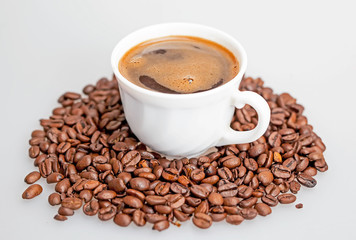 Coffee beans scattered around a cup of coffee.