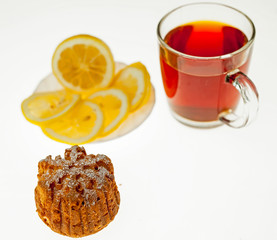 A glass of tea, lemon and cupcake.