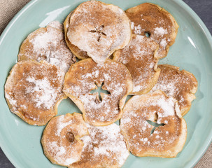 Green plate with homemade  apple chips sprinkled with powdered sugar and cinnamon.