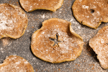 Close-up apple chips sprinkled with powdered sugar and cinnamon on grey background.