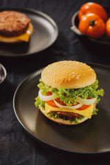 Hamburger with beef meat burger and fresh vegetables on dark background. Tasty fast food
