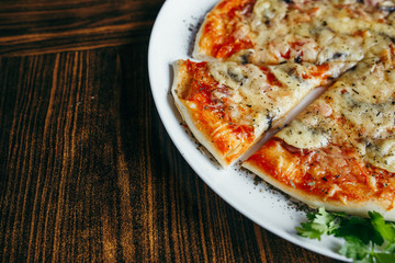 Hot pizza slice with melting cheese on a wooden table.