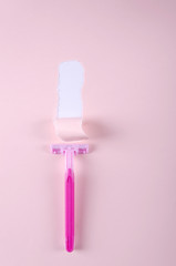 Torn paper and sharp pink razor on the pink backround.Vertical shot.Concept of safe shaving