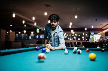 Stylish asian man wear on jeans playing pool billiard on bar.