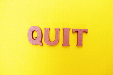 Top view Quit letters alphabet letters on Yellow background