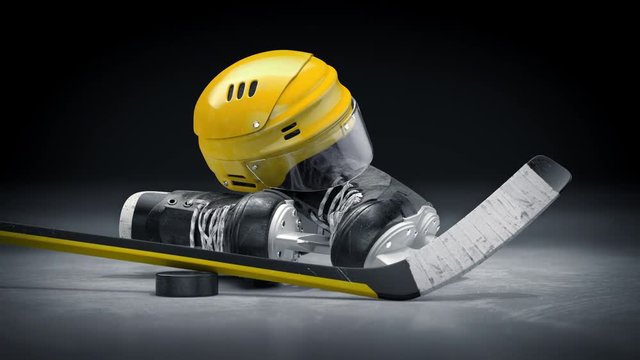 Amazing yellow hockey helmet, stick, puck and skates on a ice area