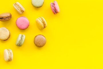 Brignt macarons for sweet break on yellow background top view mock up