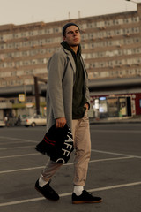 Handsome guy in stylish clothes walks on a city street at sunset