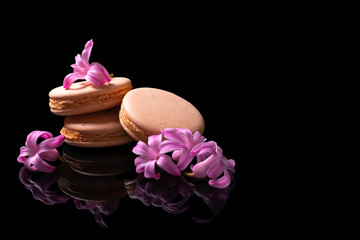Sweet macarons or macaroons decorated with blooming flowers on a black background.