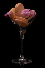Sweet macarons or macaroons decorated with blooming flowers on a black background
