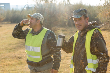 Hunter with a german drathaar and spaniel, pigeon hunting with dogs in reflective vests	